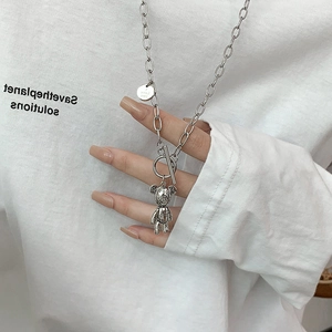 Detail of silver double-layered necklace featuring a 3D bear pendant and OT buckle