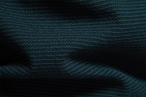 Gros plan sur la maille haut de gamme vert foncé et bleu marine de ce pull d'affaires chic