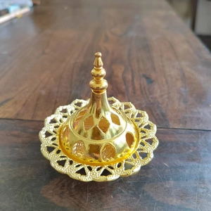 Close-up of golden hollow metal incense burner lid with vintage Middle Eastern patterns