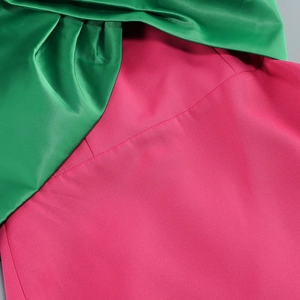 Detailed close-up of green satin and magenta fabric stitching for evening gown