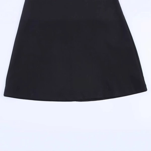 Gros plan de l'ourlet d'une robe dos nu noire montrant le tissu tissé sur fond blanc