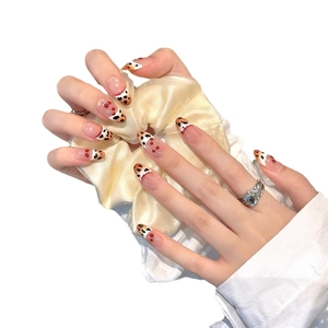 Handmade press-on nails with brown leopard pattern and oval shape on a soft silk background