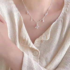Detail of 925 sterling silver butterfly pendant necklace with small pearls on model