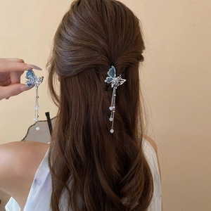 Détail d'une pince à cheveux papillon avec glands argentés et perles bleues dégradées