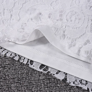 Close-up of intricate white lace embroidery and delicate hem stitching on the garment