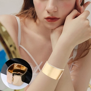 Detailed view of golden wide metal bracelet with side spring hinge on model wrist