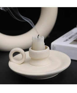 Close-up of matte ceramic candle holder with loop handle and smoking white candle