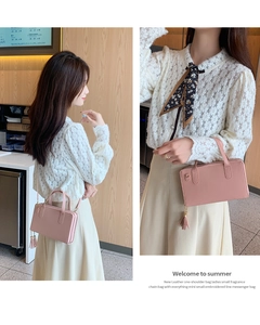 Detail of light pink dual-layer crossbody bag featuring a stylish tassel and metal chain strap