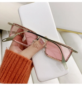 Detalle de gafas de sol rosadas sin montura con marco dorado y pedrería brillante