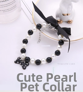 Detail of pearl pet collar with black bow and rhinestone bone charm on a white tray