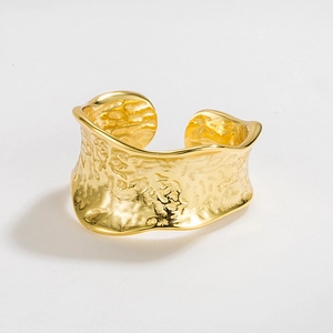 Minimalist wide gold open ring with irregular hammered texture and metallic glossy finish