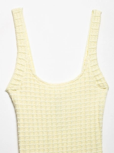 Primer plano de la textura de punto gofrado amarillo claro de un vestido ajustado elástico
