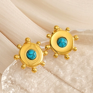 Gros plan sur des boucles d'oreilles en acier doré avec pierre turquoise de style rétro