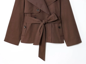 Detail of dark brown double-breasted trench jacket with matching waist belt and lapels