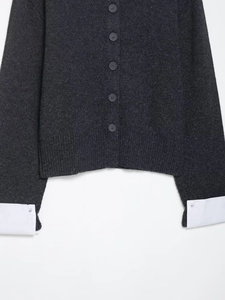 Detail of dark grey knit cardigan with white shirt cuff patchwork and buttons
