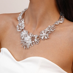 Close-up of a silver floral necklace with pearls shown on a female model