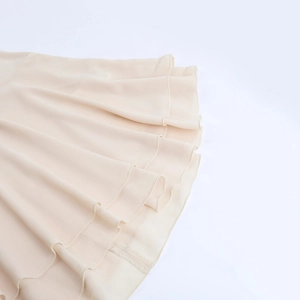 Detailed view of layered pleated chiffon skirt fabric in elegant apricot color