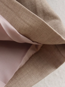 Detail of beige twill fabric with soft pink lining showing weave texture and layering
