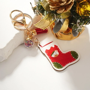 Christmas bear stocking keychain with red tassel and starry glass ball on stone surface