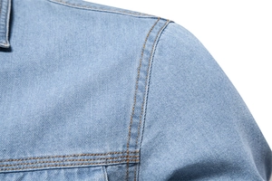 Détail d'une chemise en jean bleu clair délavé avec des surpiqûres orange contrastées
