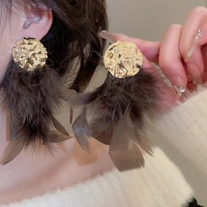 Detail view of gold feather tassel earrings on model for a bohemian vintage style
