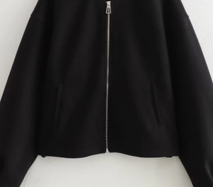 Detail view of a black bomber jacket with silver metal zipper and soft knit fabric texture