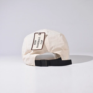 Detail of adjustable black strap and buckle on a beige waterproof short brim baseball cap