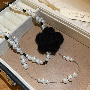 Detail of a handmade double-layer pearl necklace with a large black crochet floral pendant