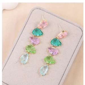 Macro view of long drop earrings with colorful pear-cut zircon stones in gold settings