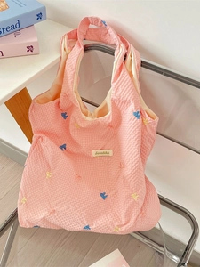 Pink waffle fabric tote bag with blue and yellow butterfly embroidery on a chair