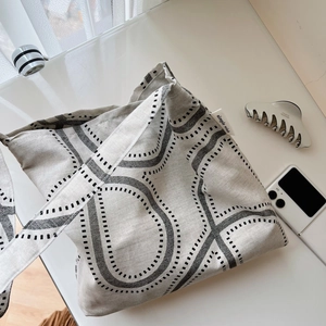 Macro detail of cotton linen shoulder bag with abstract lines and simple wish label