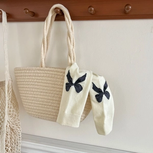 Detail of cream cotton socks with black bows hanging on wooden hooks in a soft light