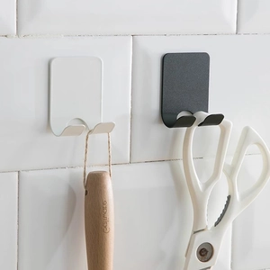 Minimalist J-shaped adhesive wall hooks in black and white hanging tools on white tile