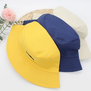 Detail of three cotton bucket hats in yellow, navy and cream with fine embroidery