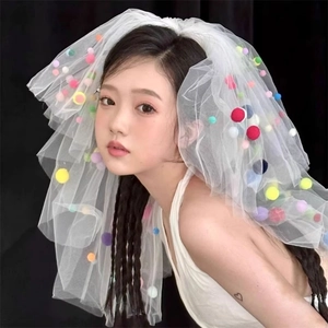 Detail of multi-layered white tulle veil featuring colorful vibrant pom-poms for parties