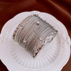 Detailed close-up of a silver multi-layer woven bangle set with sparkling rhinestones