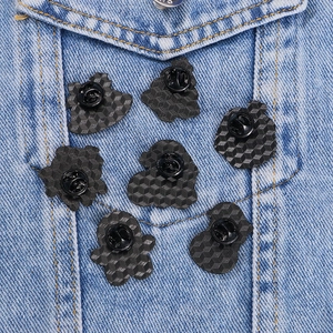 Black enamel pin backs with honeycomb texture and butterfly clasps on denim jacket