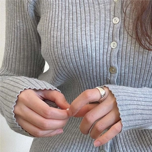 Close-up of minimalist 925 sterling silver arc ring worn on a finger with knitwear background