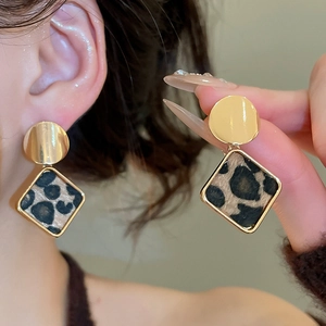 Macro detail of retro leopard print diamond-shaped earrings with gold metal frame