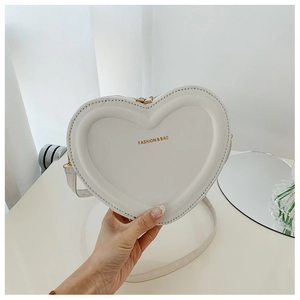 Dettaglio della borsa bianca a forma di cuore con scritta dorata e cerniera in metallo