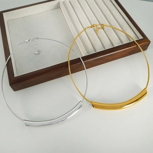 Minimalist 18k gold and silver curved tube snake chain necklace on wood display