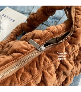 Close-up of brown velvet cloud bag with pleated texture and silver metal zipper detail