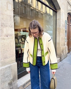 Close-up of beige quilted jacket with green contrast panels and brown piping detail