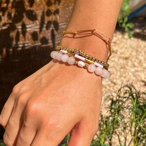Détail d'un bracelet multicouche doré avec cristal rose et pendentif en cœur
