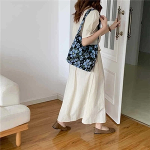 Blue floral canvas hobo bag styled with a cream dress for a vintage commute look
