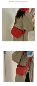 Detail view of red faux leather saddle bag worn with a khaki trench coat for women