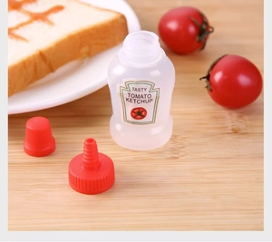 Mini plastic squeeze bottle for ketchup with red cap on a rustic wooden surface