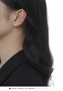 Macro shot of gold-layered ear cuff with sparkling zircon inlay worn on model's ear