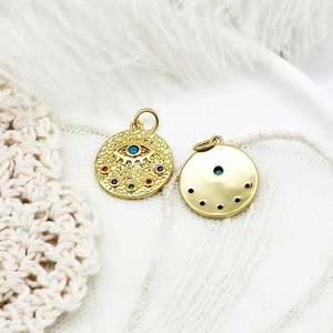 Detailed view of gold evil eye pendant with colorful zircons on lace and feather