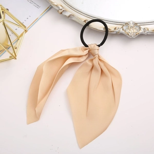 Detail of elegant champagne silk hair scrunchie with a large bow and long ribbons